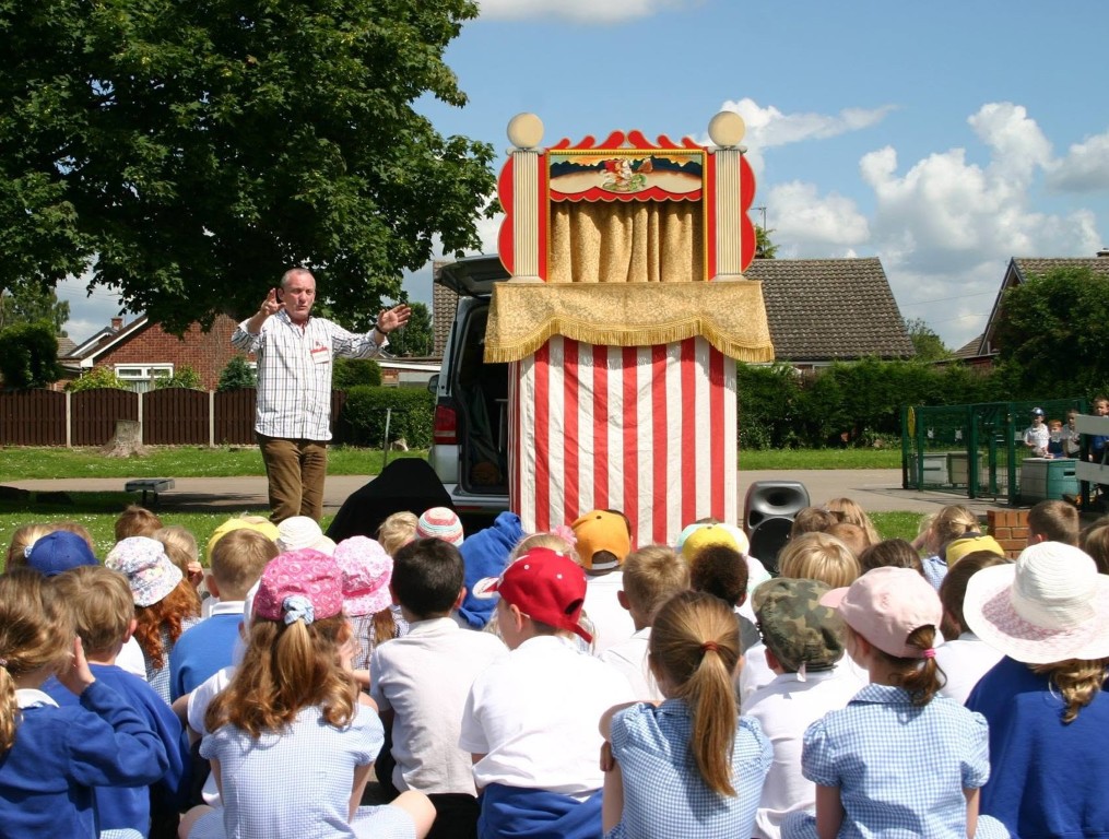 A traditional red and white striped Punch and Judy theatre set up in a school playground